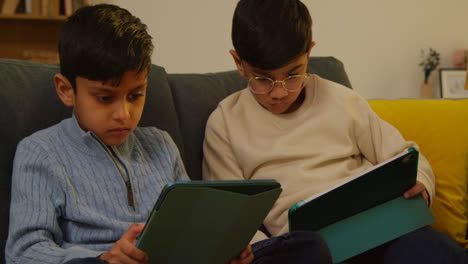 Zwei-Junge-Jungen-Sitzen-Zu-Hause-Auf-Dem-Sofa-Und-Spielen-Spiele-Oder-Streamen-Auf-Digitale-Tablets-9